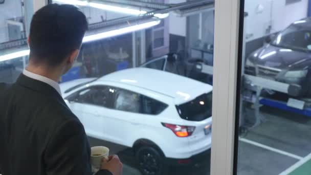 Joven hombre de negocios bebiendo café y mirando por la ventana — Vídeos de Stock