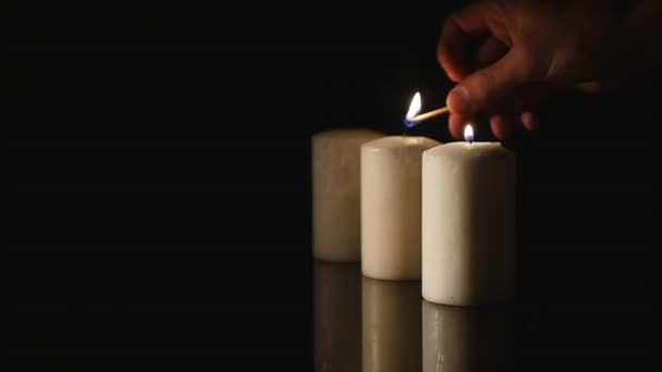 Hände entzündeten eine Kerze auf schwarzem Hintergrund — Stockvideo
