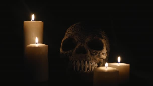 Four lighted candles and a skull on a black background — Stock Video