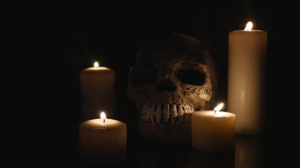 Four lighted candles and a skull on a black background — Stock Video