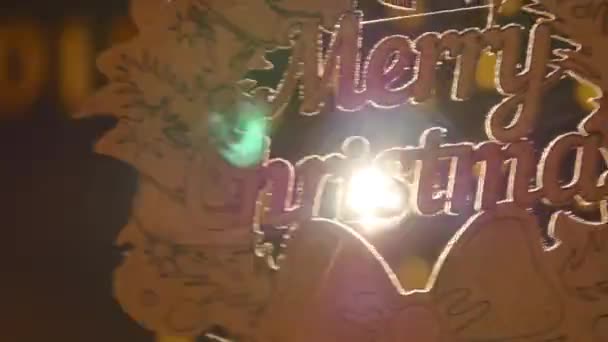 Houten bord met de tekst Merry christmas op de achtergrond van kerstverlichting — Stockvideo