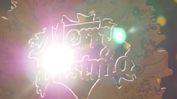 Houten bord met de tekst Merry christmas op de achtergrond van kerstverlichting — Stockvideo