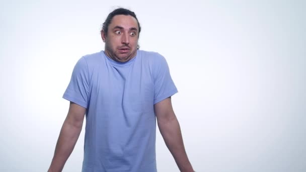 Retrato del guapo hombre emocional en camiseta en una pose que no conozco sobre fondo blanco — Vídeo de stock