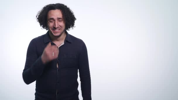 Ung vacker man bär svart tröja högljutt skratta isolerad på vit bakgrund — Stockvideo