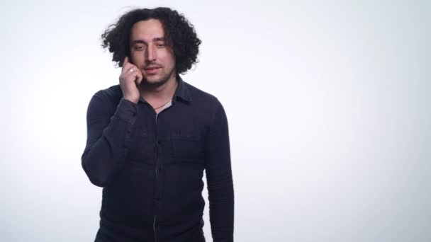 Portrait of a young beautiful man speaks on the phone and smiling on white background — Stock Video