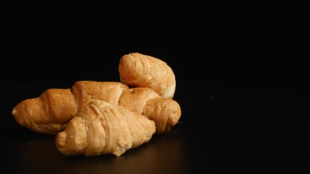 Tres croissants giran sobre un fondo negro — Vídeos de Stock