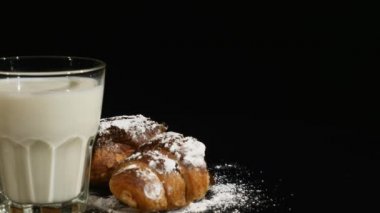 süt kruvasan ile siyah bir arka plan üzerinde döndürme