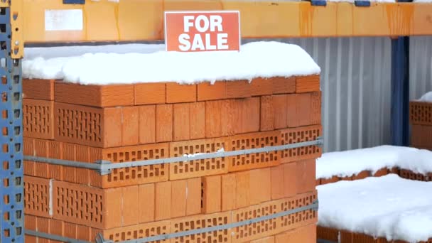 Stack of orange clay brick with snow "For sale" words — Stock Video