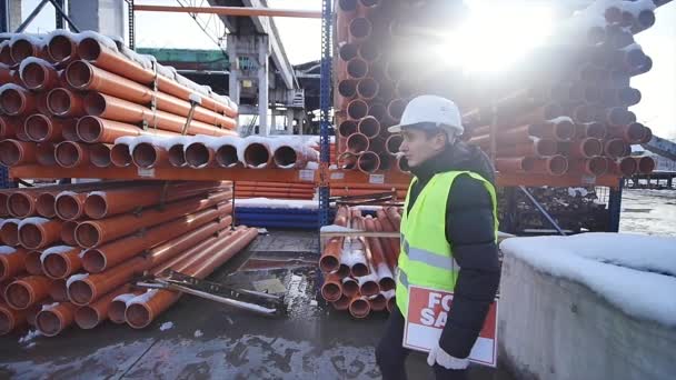 Materiais de construção e de construção para venda armazenados em prateleiras de metal ao ar livre em um pátio de armazém, juntamente com paletes de madeira para carga, distribuição e armazenamento — Vídeo de Stock