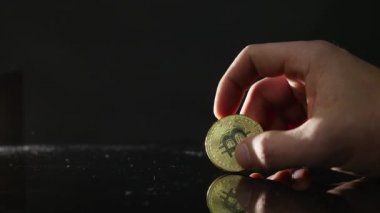 adam elinde bir altın bitcoin siyah arka plan üzerinde tutar.