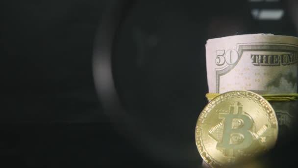 Bitcoin y los billetes de dólar retorcidos sobre un fondo negro — Vídeo de stock