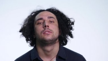 Beyaz arka planda siyah gömlekli karizmatik sakallı genç adam farklı duygular gösterir