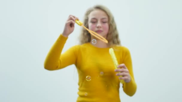 Teenage girl lets out soap bubbles. White background — Stock Video