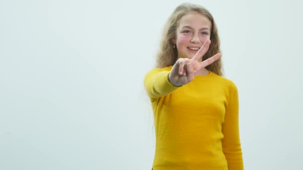 Χαρούμενη χαμογελαστή όμορφη νεαρή γυναίκα που δείχνει δύο δάχτυλα ή χειρονομία νίκης, απομονωμένη πάνω σε λευκό φόντο — Αρχείο Βίντεο