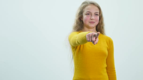 Menina jovem apontando o dedo para a câmera na frente do fundo branco — Vídeo de Stock