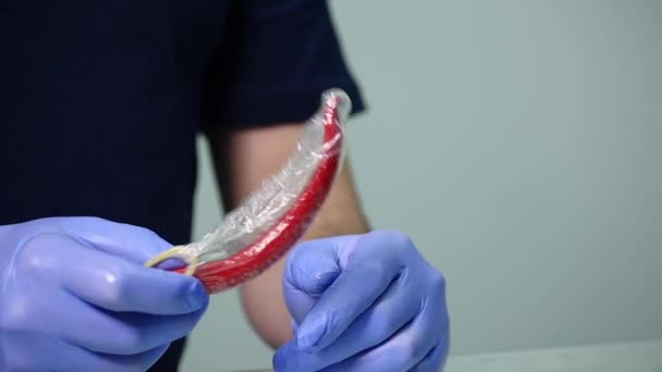 A man wears a condom on chili pepper — Stock Video