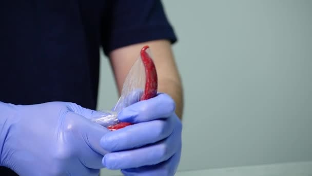 A man wears a condom on chili pepper — Stock Video