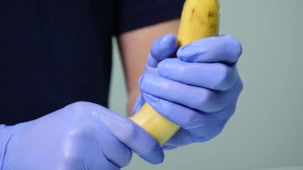 A mans hand zetten een condoom op een banaan. Het concept van veilige sex en preventie van seksueel overdraagbare aandoeningen — Stockvideo