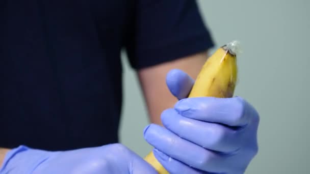 A mans ręka zakładanie prezerwatywy na banana. Koncepcja bezpiecznego seksu i profilaktyki choroby przenoszone drogą płciową — Wideo stockowe