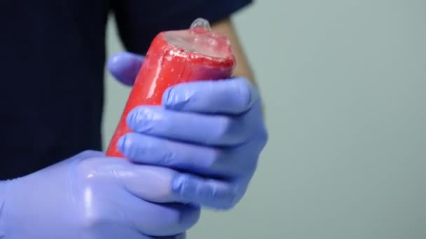 Händerna på en man som bär en kondom på ett ljus — Stockvideo