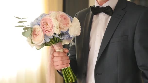 Ženicha drží elegantní svatební kytice