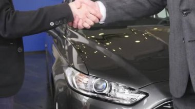 Yeni araba arka plan üzerinde iki adamın el sıkışma. El sıkışma ile tebrik erkeklerin kapatın. İş ortakları el sıkışma