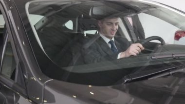 Bir adam iç araç olup olmadığını denetler. Otomatik iş, araba Satılık, teknoloji ve insan kavramı - auto göstermek ya da salon araba satıcısı ile mutlu erkek. Bir satıcı motor gösterisi ile genç adam