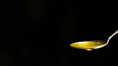 Siyah arka plan karşı kaşık akan bal