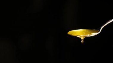 Siyah arka plan karşı kaşık akan bal