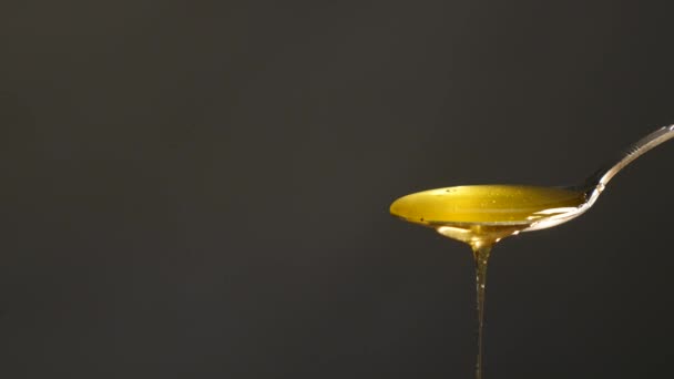 Miel fluyendo de cuchara contra fondo negro — Vídeo de stock