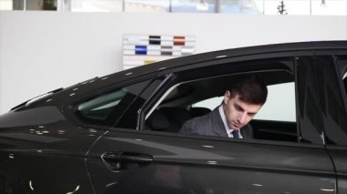 Bir adam iç araç olup olmadığını denetler. Otomatik iş, araba Satılık, teknoloji ve insan kavramı - auto göstermek ya da salon araba satıcısı ile mutlu erkek. Bir satıcı motor gösterisi ile genç adam