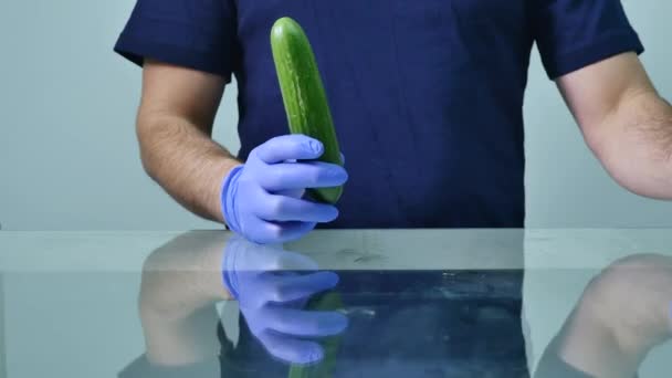 Manos masculinas sosteniendo pepino y condón. Concepto de sexo seguro — Vídeos de Stock