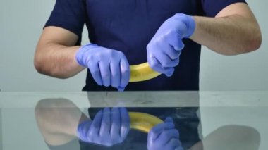 A mans el bir prezervatif bir muz üzerinde koyarak. Güvenli seks ve cinsel yolla bulaşan hastalıklardan korunma