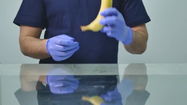 Uma mão de homem a pôr um preservativo numa banana. O conceito de sexo seguro e prevenção de doenças sexualmente transmissíveis — Vídeo de Stock