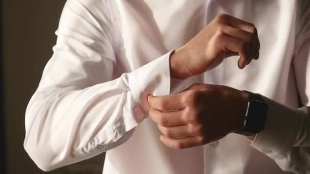 Vue rapprochée de jeunes mains masculines s'habillant le matin. Manchettes homme boutons sur une chemise, se préparer pour le mariage — Video