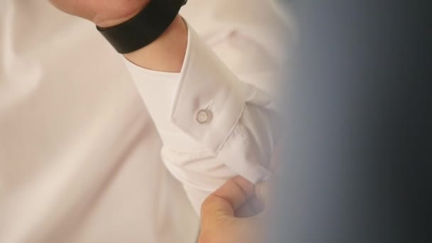 Vista de perto de jovens mãos masculinas se vestindo de manhã. Botões de homem algemas em uma camisa, se preparando para o casamento — Vídeo de Stock