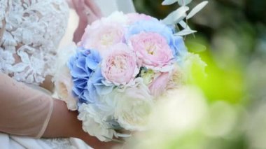 Beyaz gelinlik giymiş genç gelinin elinde güzel gelin buketi