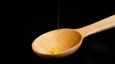 siyah arka plan üzerine bir tahta bal ayı den damlayan bal