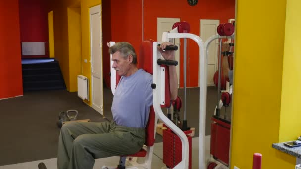 Senior homme utilisant un entraîneur dans la salle de gym — Video
