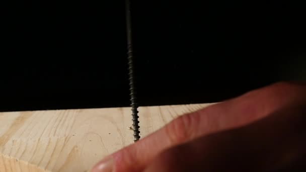 De man draait de schroeven in de planken met behulp van een schroevendraaier. — Stockvideo