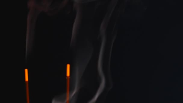 Крупный план горящих благовонных палочек с дымом на черном фоне — стоковое видео