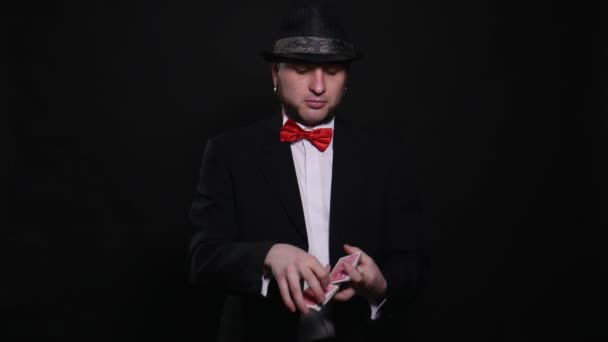 Young magician shows magic playing card trick show concept trick on black background — Stock Video