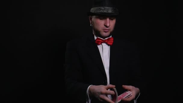 Young magician shows magic playing card trick show concept trick on black background — Stock Video