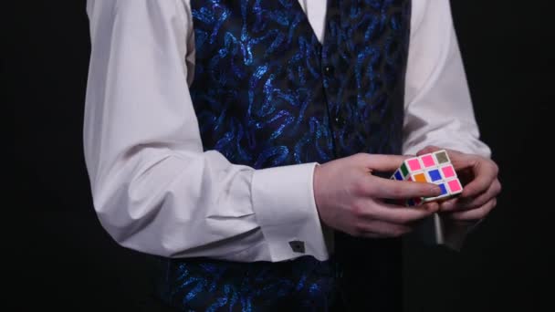 Hands of a magician show us un-assembled Rubiks cube, then make a magical passe, and the cube turns in a split of a second into a fully assembled one — Stock Video