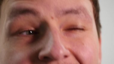 göz kırpıyor ve gülümseyen bir genç adam. yakın çekim.