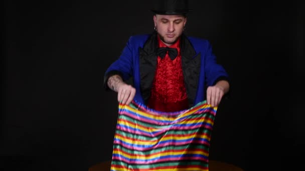 Magician shows trick with scarf and candle on dark background — Stock Video
