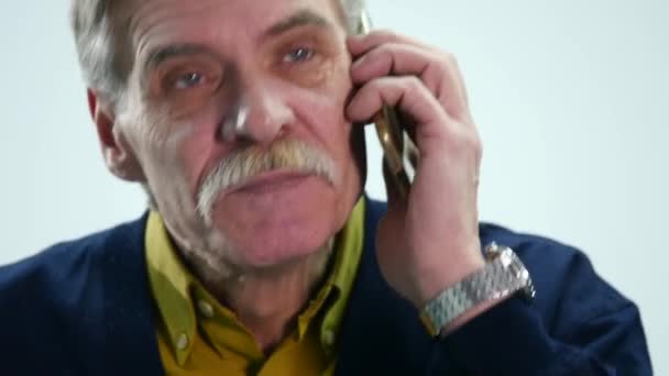 Сердитый пожилой человек, разговаривающий по мобильному телефону — стоковое видео