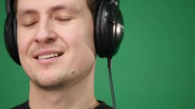 Mutlu genç dans Kulaklığımda adam ve yeşil zemin üzerine müzik dinle