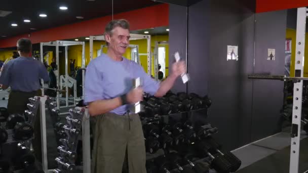 Viejo activo haciendo ejercicio con pesas en un gimnasio — Vídeos de Stock