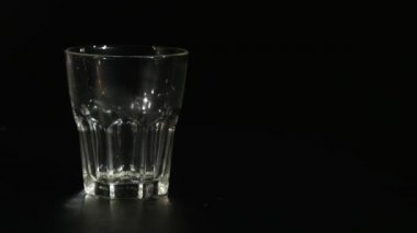 Siyah arka plan üzerine bir bardak içine süt uzun bir akış içinde dökme